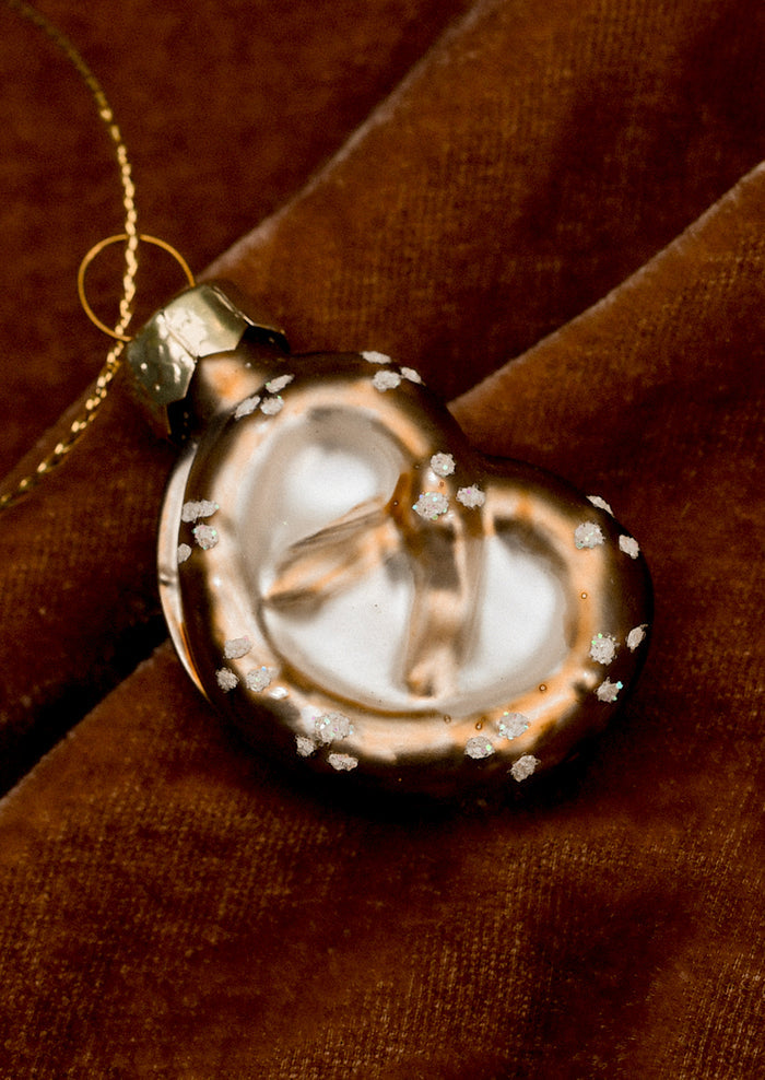 A small glass ornament in the shape of a soft pretzel.