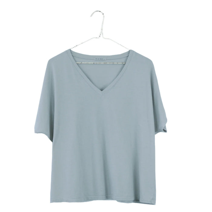 A misty sage colored V-neck boxy tee hanging on a hanger against a white background.