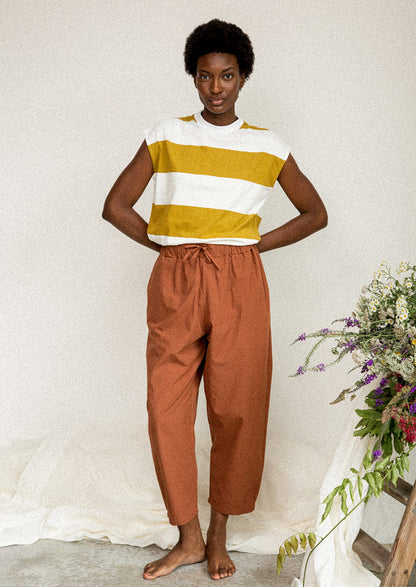 A woman wearing a white and mustard striped muscle tee.