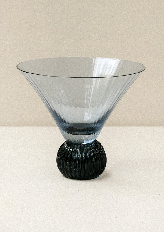 A short blue glass martini glass with ribbed, flared shape.