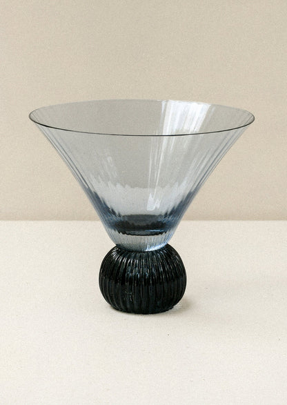 A short blue glass martini glass with ribbed, flared shape.