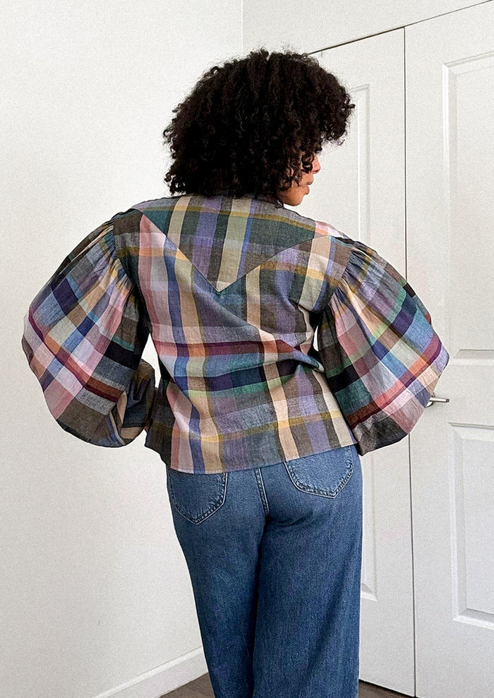 A person wearing a plaid print blouse with blouson sleeves.