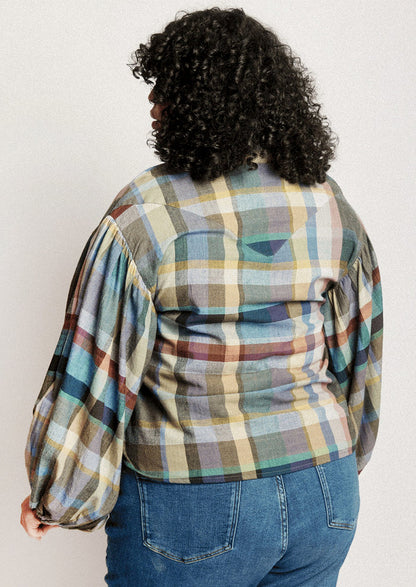 A person wearing a plaid print blouse with blouson sleeves.