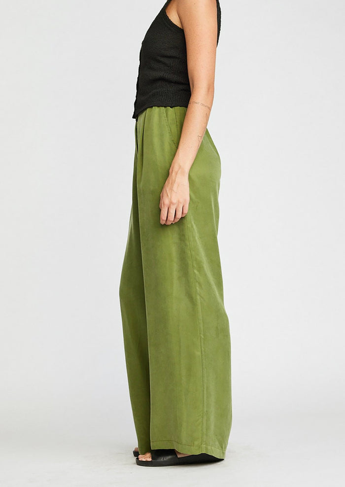 A person wearing a pair of cupro trousers in kelp green.