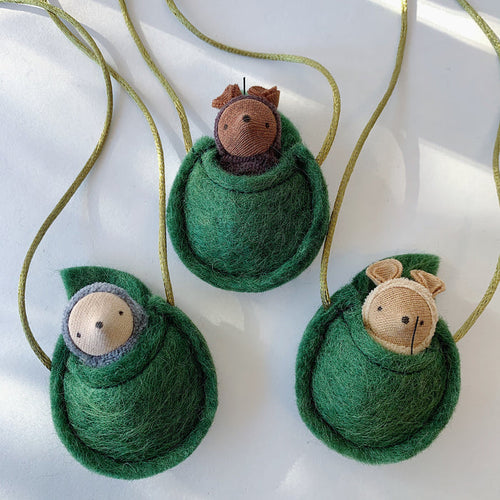 Fairy Shadow Critter Necklaces, overhead view of all three styles on a white surface, showing grey mole, chocolate mouse, and beige mouse critter figures peeking out of handmade felted green wool egg-shaped pouches on gold metallic cords