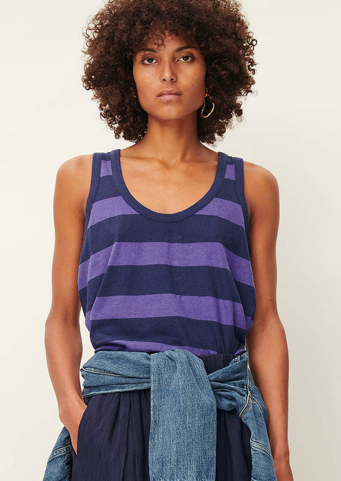 A woman wearing a scoop neck tank top in blue and purple stripes.
