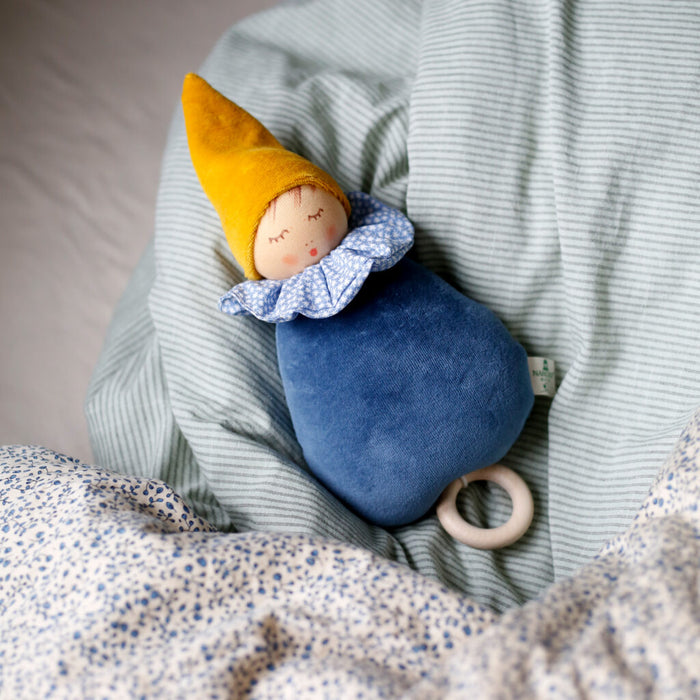 A blue music box doll with a fairy tale theme, resting on a striped blanket.