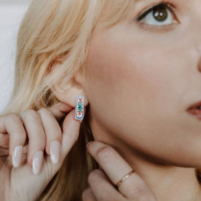 Handpainted floral ceramic stud earrings by Crown & Heart featuring colorful flower designs on white ceramic.