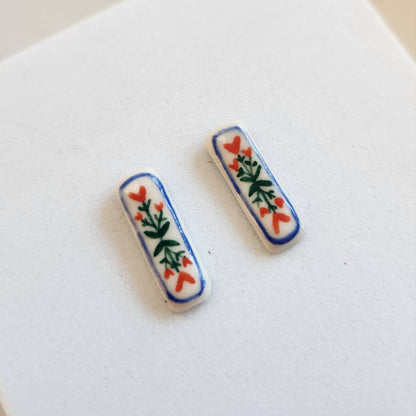 Handpainted floral ceramic stud earrings by Crown & Heart featuring colorful floral designs on small ceramic studs.