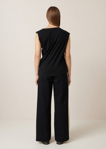 A woman wearing a black cap sleeve t-shirt with drape front detail.