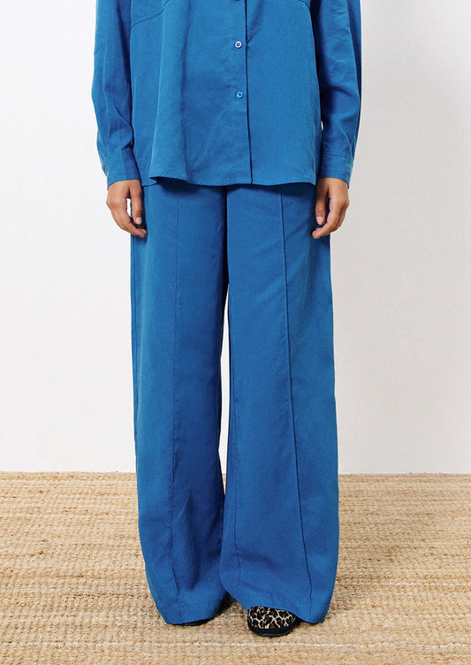 Person wearing a blue outfit with wide-leg pants on a neutral background