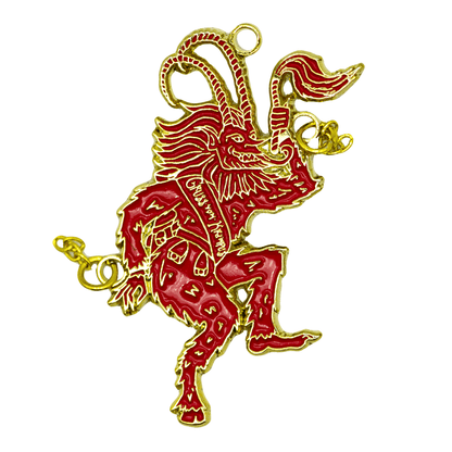 A red and gold ornament of Krampus sticking his tongue out and flailing his chains as he dances. He wears a sash that reads "Gross Vom Krampus".