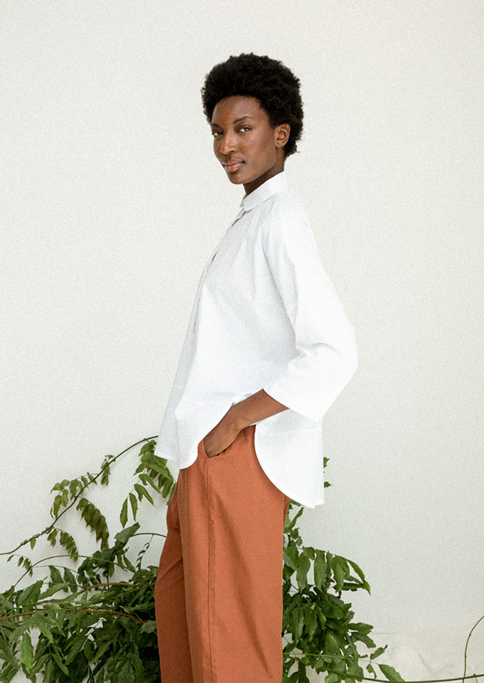 A woman wearing a blousy white cotton shirt.