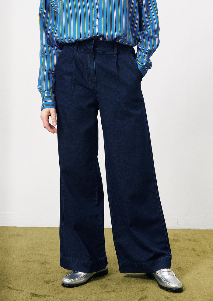 A woman wearing a pair of wide leg trouser style jeans in dark inky denim.