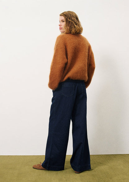 A woman wearing a pair of wide leg trouser style jeans in dark inky denim.