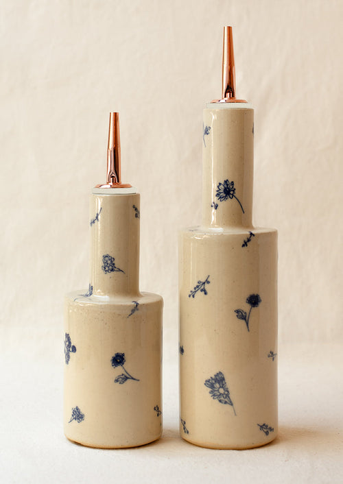 A pair of short and tall ceramic pouring bottles with blue floral pattern.