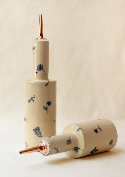 A pair of short and tall ceramic pouring bottles with blue floral pattern.