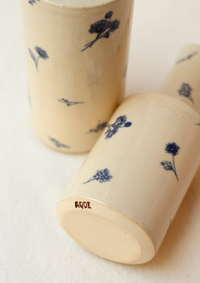 A pair of short and tall ceramic pouring bottles with blue floral pattern.