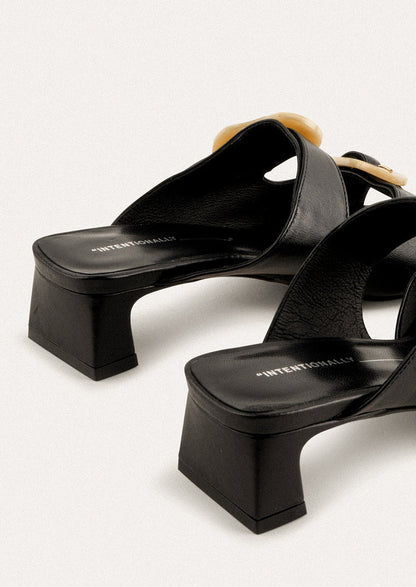 A square toe heeled sandal in black with double tan buckle detail.