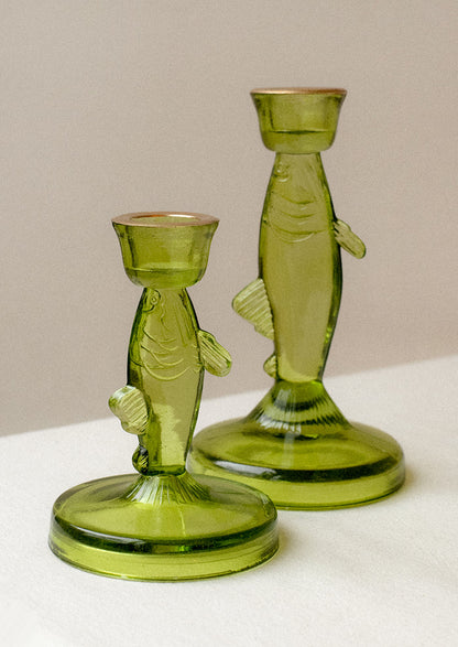 A green tinted translucent glass candle holder in the shape of a fish.
