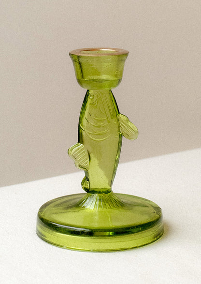 A green tinted translucent glass candle holder in the shape of a fish.