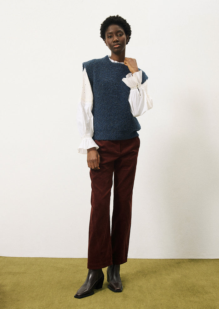 A woman wearing a cap sleeve sweater vest in marled blue knit with boucle texture.