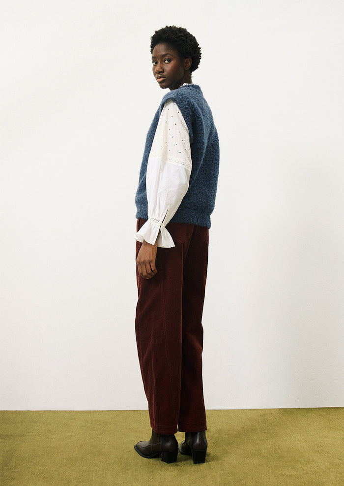 A woman wearing a cap sleeve sweater vest in marled blue knit with boucle texture.