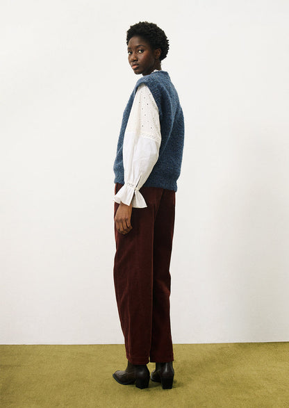 A woman wearing a cap sleeve sweater vest in marled blue knit with boucle texture.