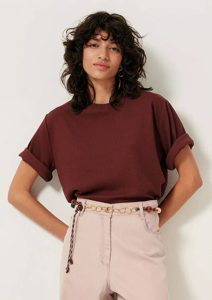 A woman wearing a short sleeve t-shirt with cuffs rolled up.