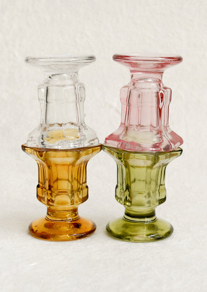Footed glass candle holders in assorted colors.