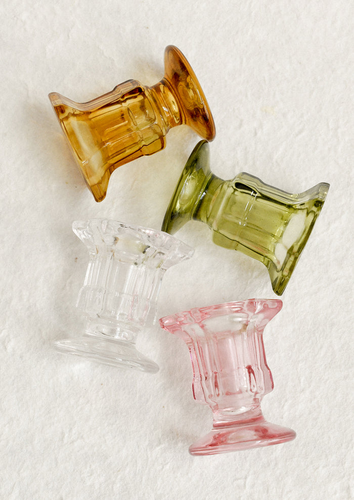 Footed glass candle holders in assorted colors.